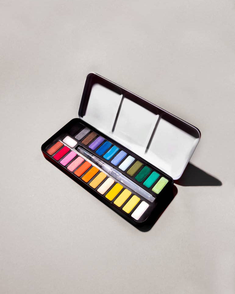 Open watercolor palette with various colors on a light gray background
